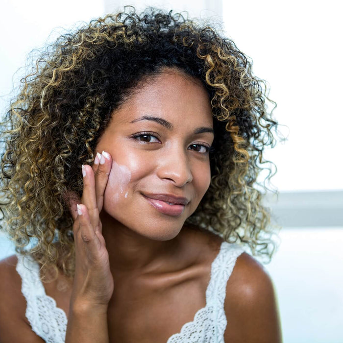 Young woman applying moisturizer
