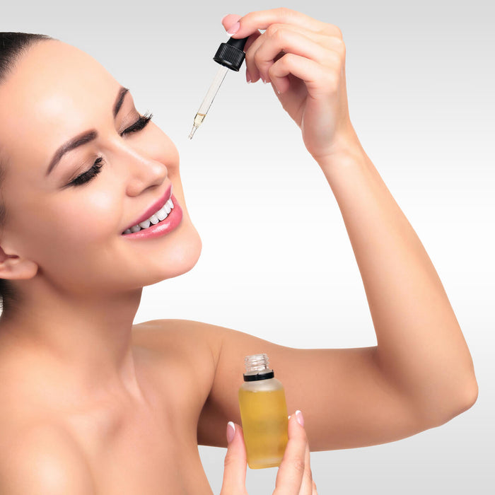 Closeup shot of cosmetic oil applying on young woman's face with pipette. Beauty therapy concept. Grey steel background